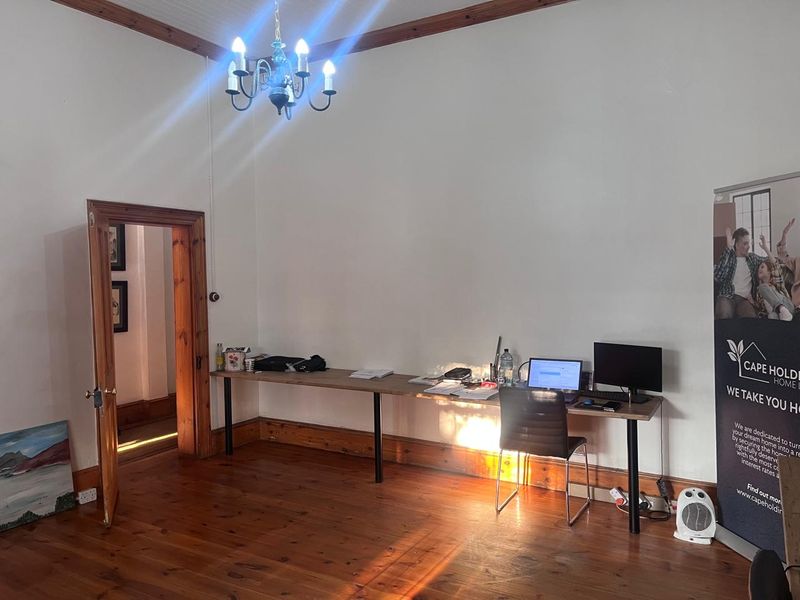 Spacious office area featuring polished timber flooring, traditional timber door frames, and a classic chandelier, offering a bright and functional workspace.