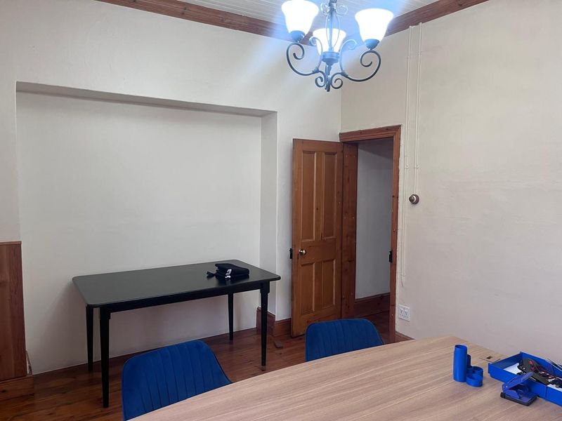 A functional office space featuring timber flooring, classic timber door frames, and a central ceiling light fixture, suitable for a professional work environment.