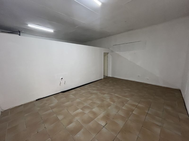 An empty, open-plan retail space featuring tiled flooring, fluorescent lighting, and existing plumbing connections, suitable for various commercial fit-out configurations.