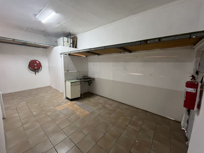 Functional utility space featuring tiled flooring, a stainless steel sink, built-in shelving, and essential fire safety equipment.