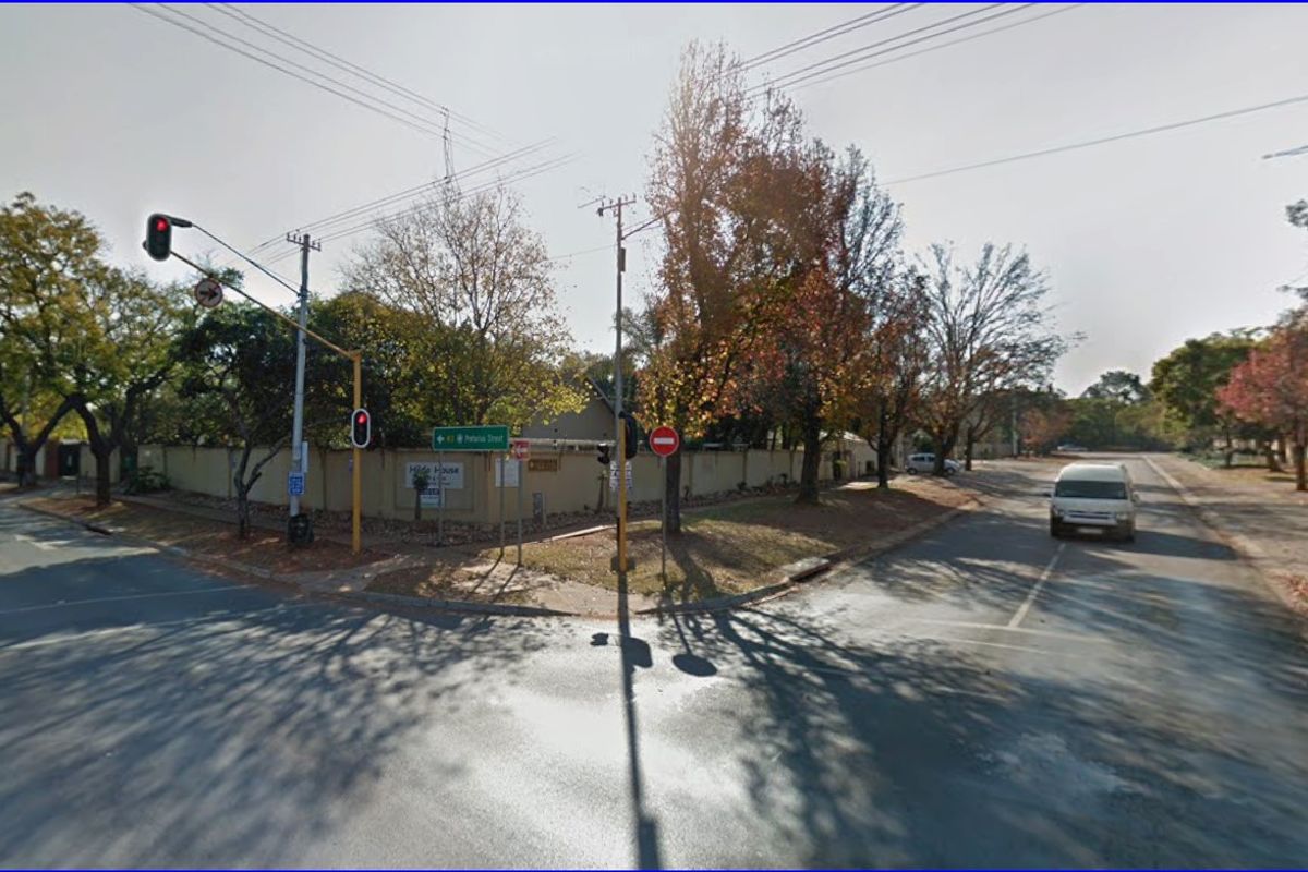 Street view of the commercial property corner, featuring perimeter walling and proximity to local traffic infrastructure.