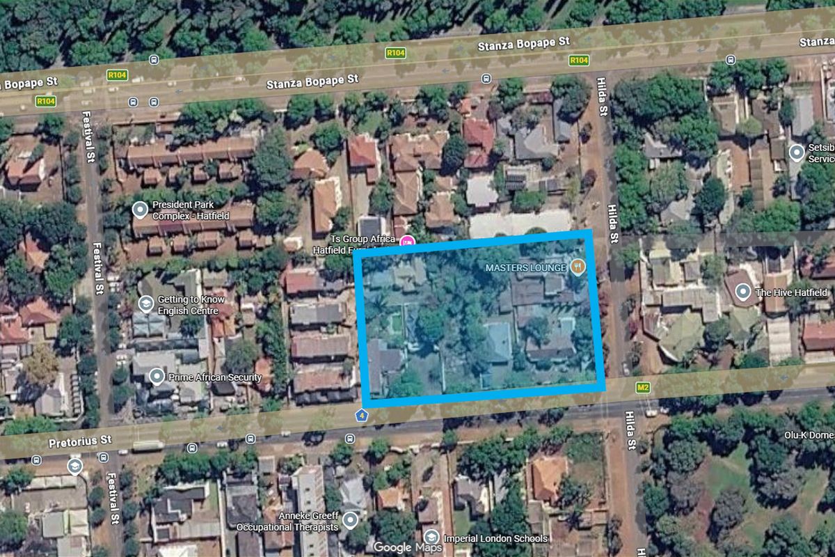 Aerial view of a commercial land parcel located in a developed urban area with established vegetation and existing building structures.