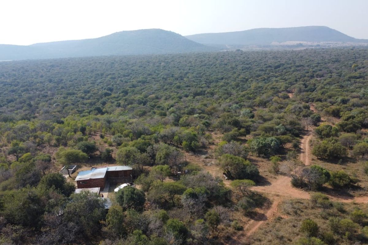 An aerial view of a rural farm property surrounded by extensive natural bushveld and rolling hills.