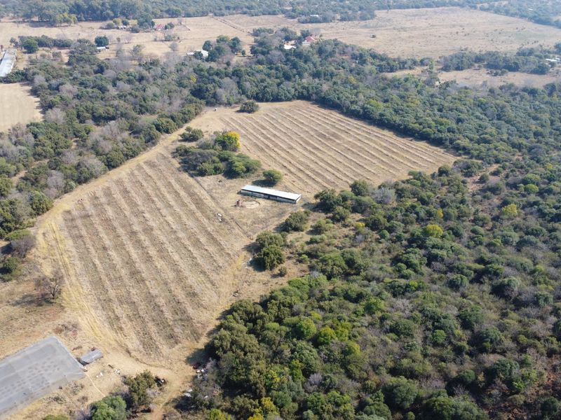 Aerial view of a large farm property featuring expansive agricultural land, natural vegetation, and a central outbuilding structure.