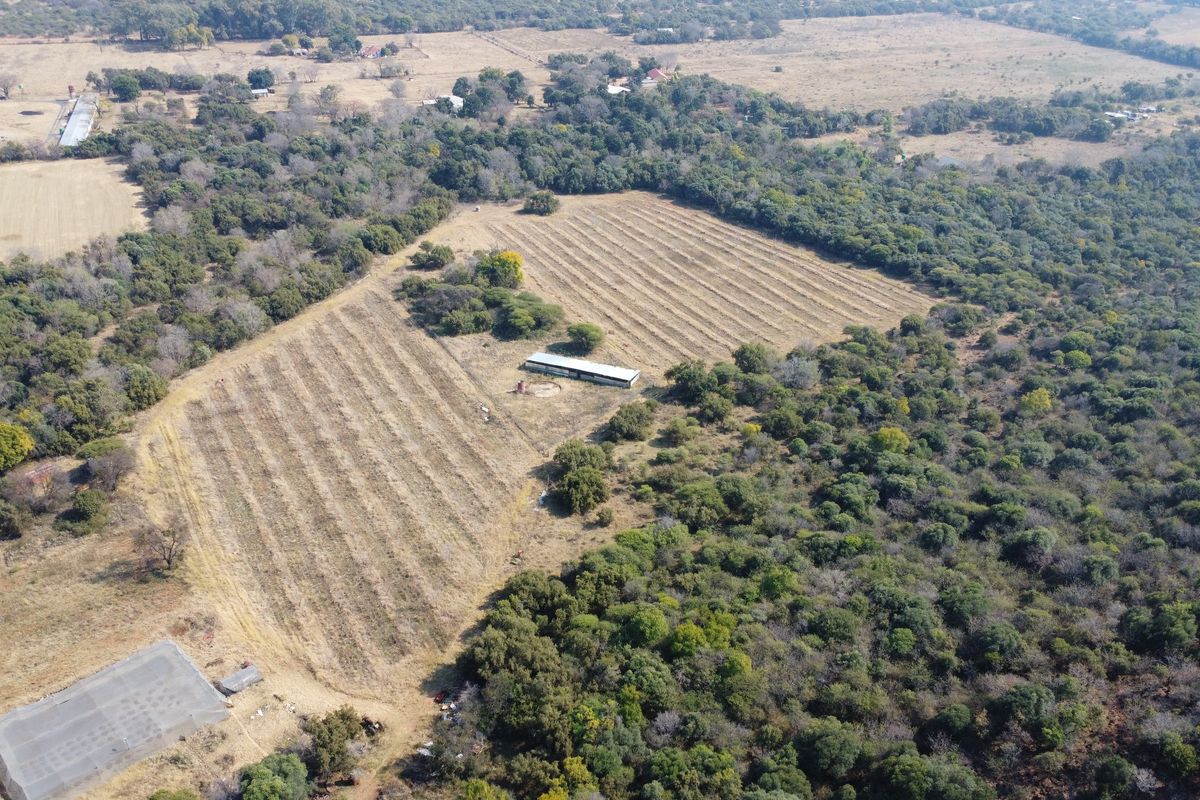 Aerial view of a large farm property featuring expansive agricultural land, natural vegetation, and a central outbuilding structure.