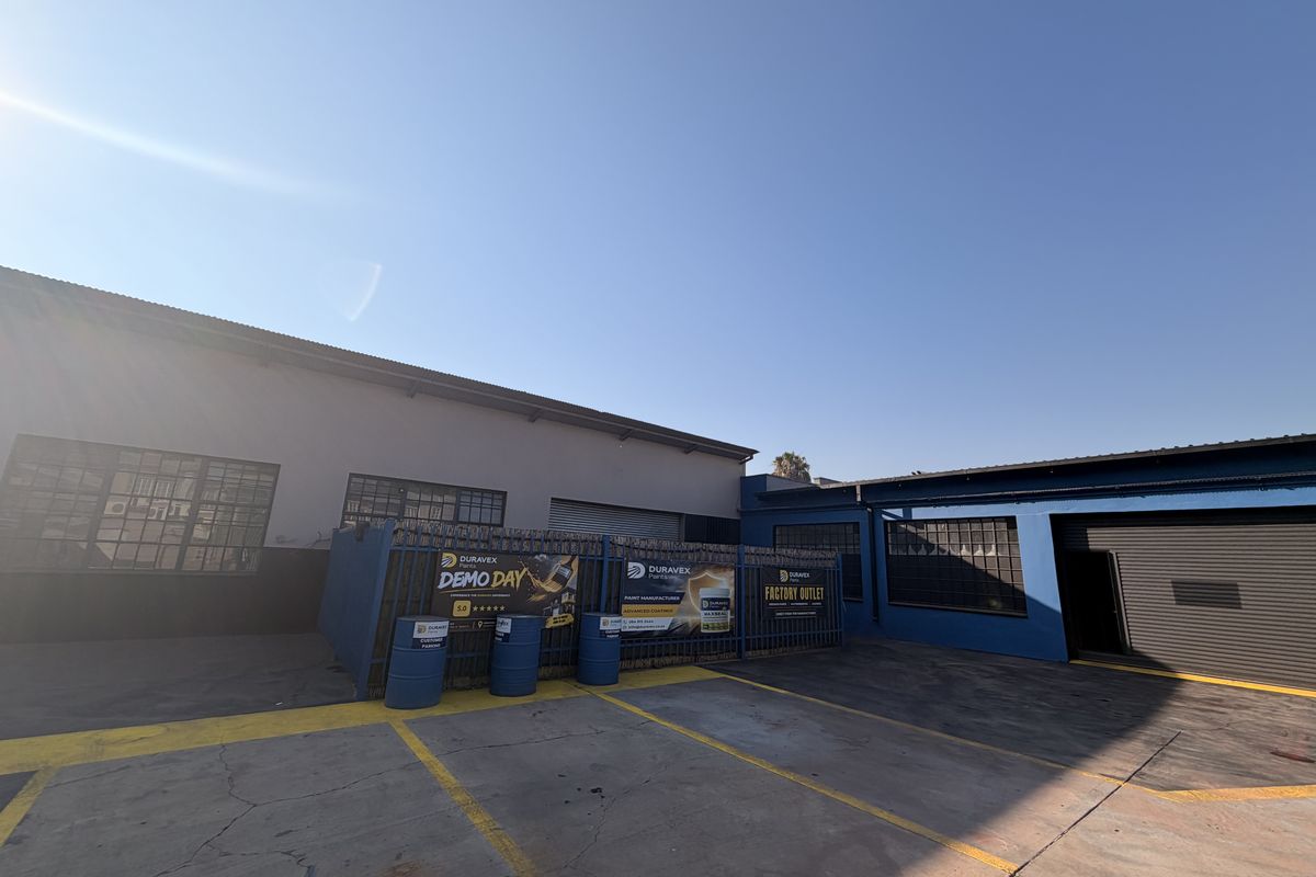 Commercial property exterior featuring a paved yard area, roller shutter access, and secure perimeter fencing, suitable for industrial or retail operations.