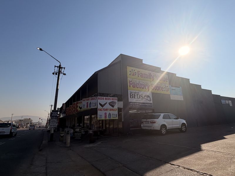 Commercial property exterior featuring large signage, metal facade, and an adjacent paved parking area along a main road.