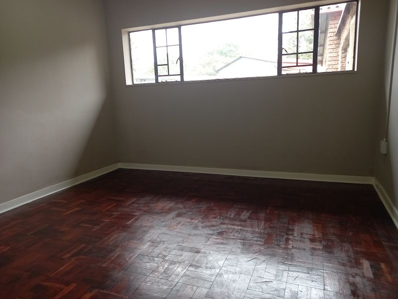 An empty office space featuring classic parquet flooring and large steel-framed windows, providing a neutral and versatile work environment.