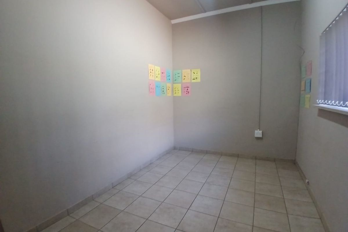 A vacant office space featuring neutral painted walls, tiled flooring, and a window with vertical blinds.