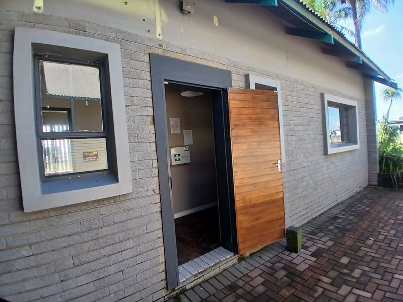 Exterior view of an office building featuring a brick facade, timber entrance door, and paved walkway area.