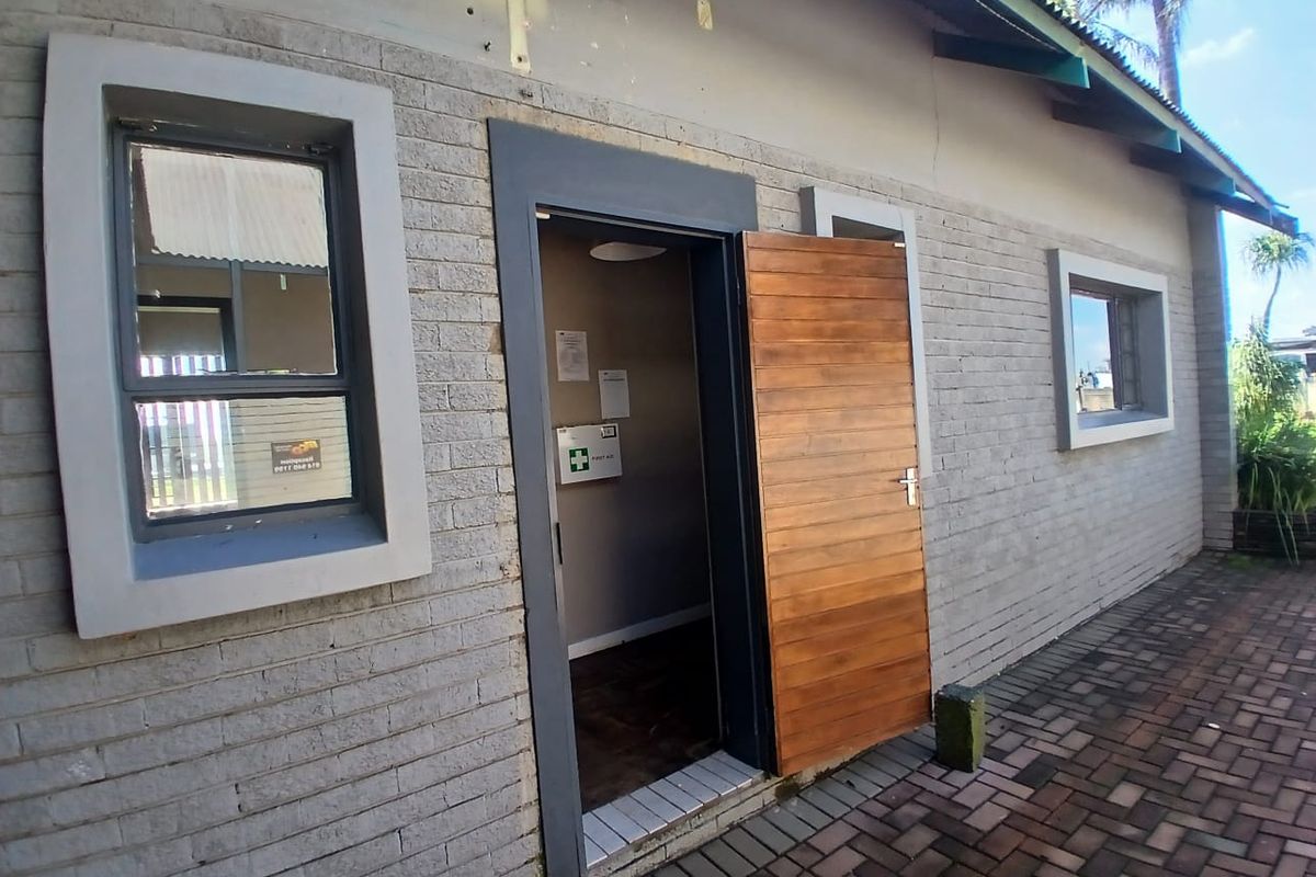 Exterior view of an office building featuring a brick facade, timber entrance door, and paved walkway area.