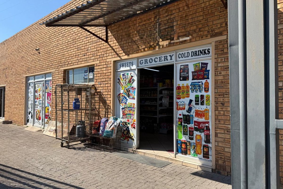 Commercial storefront featuring a face brick facade, metal awning, and glass entrance doors with retail signage.