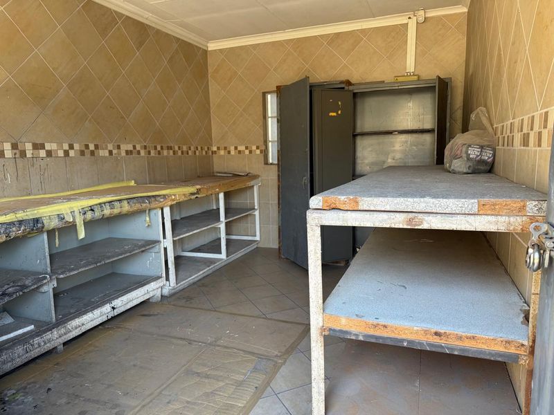 A functional utility or storage space featuring tiled walls, tiled flooring, and built-in metal shelving units, suitable for various commercial storage or prep requirements.