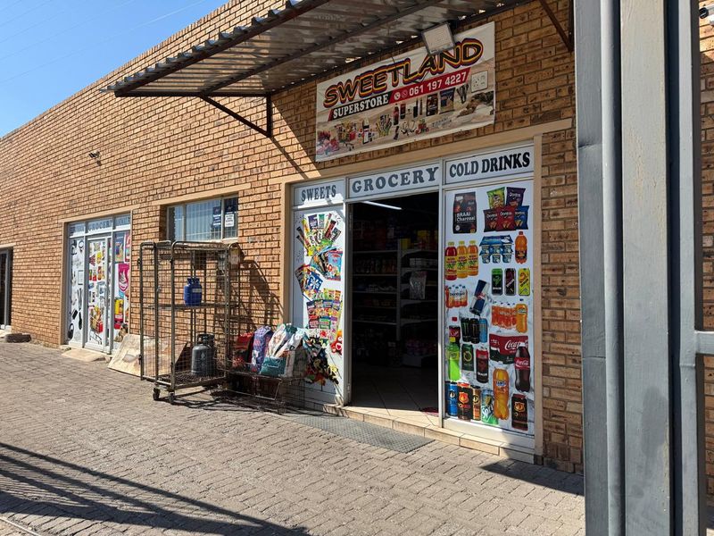 Front exterior view of a commercial retail storefront featuring brick construction, a metal awning, and glass entrance doors with signage.