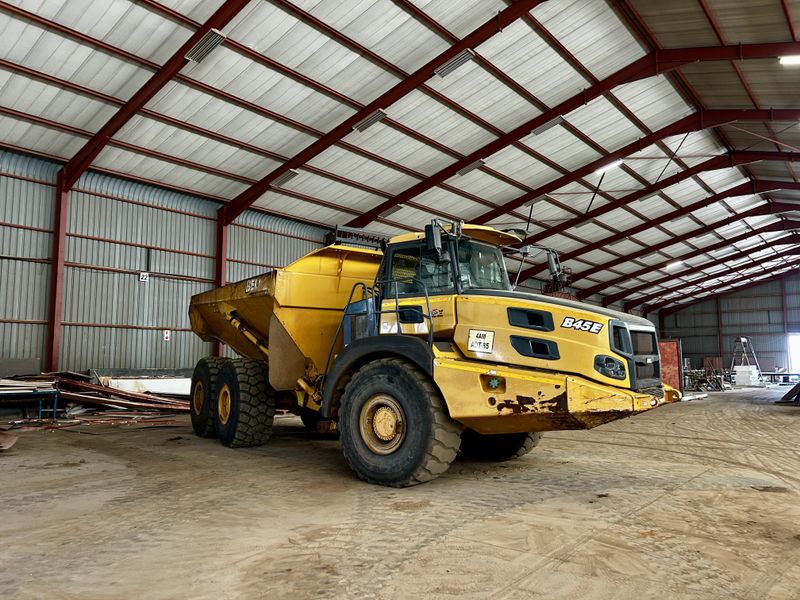 Spacious industrial warehouse featuring a steel portal frame structure, corrugated metal walls, and durable concrete flooring, currently utilized for heavy machinery storage.