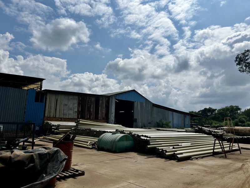 Exterior view of an industrial warehouse facility featuring corrugated metal cladding and a large concrete yard area used for storage.