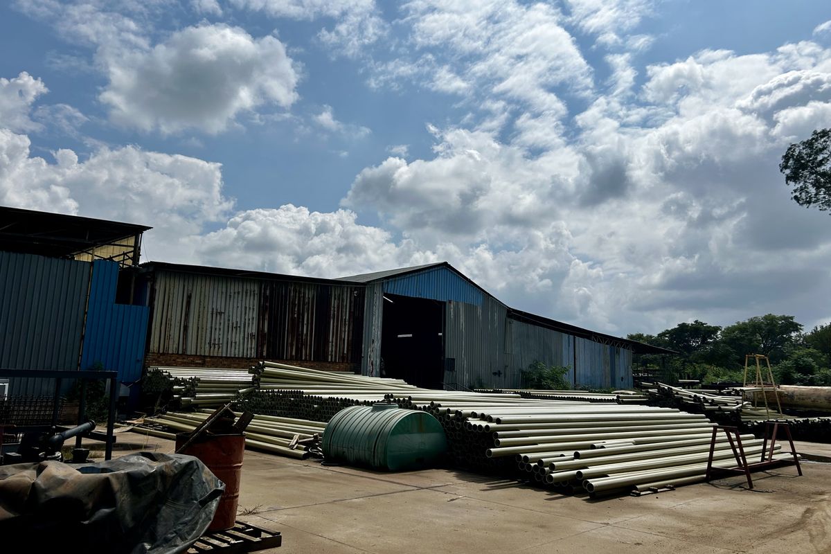 Exterior view of an industrial warehouse facility featuring corrugated metal cladding and a large concrete yard area used for storage.
