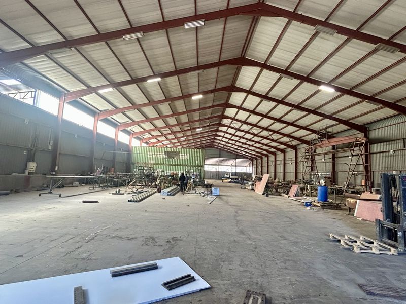 Spacious industrial warehouse featuring a steel portal frame, high ceilings with integrated skylights, and durable concrete flooring suitable for manufacturing or storage operations.
