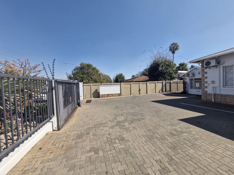 Exterior view of the office property featuring a paved driveway, secure perimeter wall with electric fencing, and a sliding gate entrance.