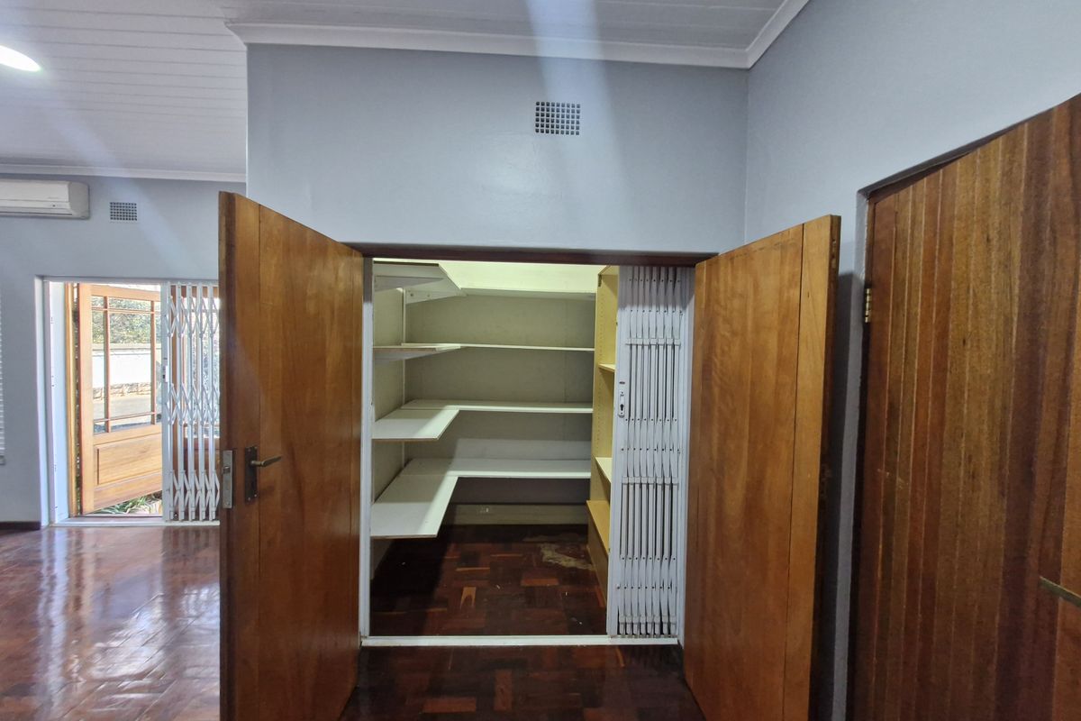 A functional utility or storage space featuring built-in shelving, parquet flooring, and secure timber double doors within an office environment.
