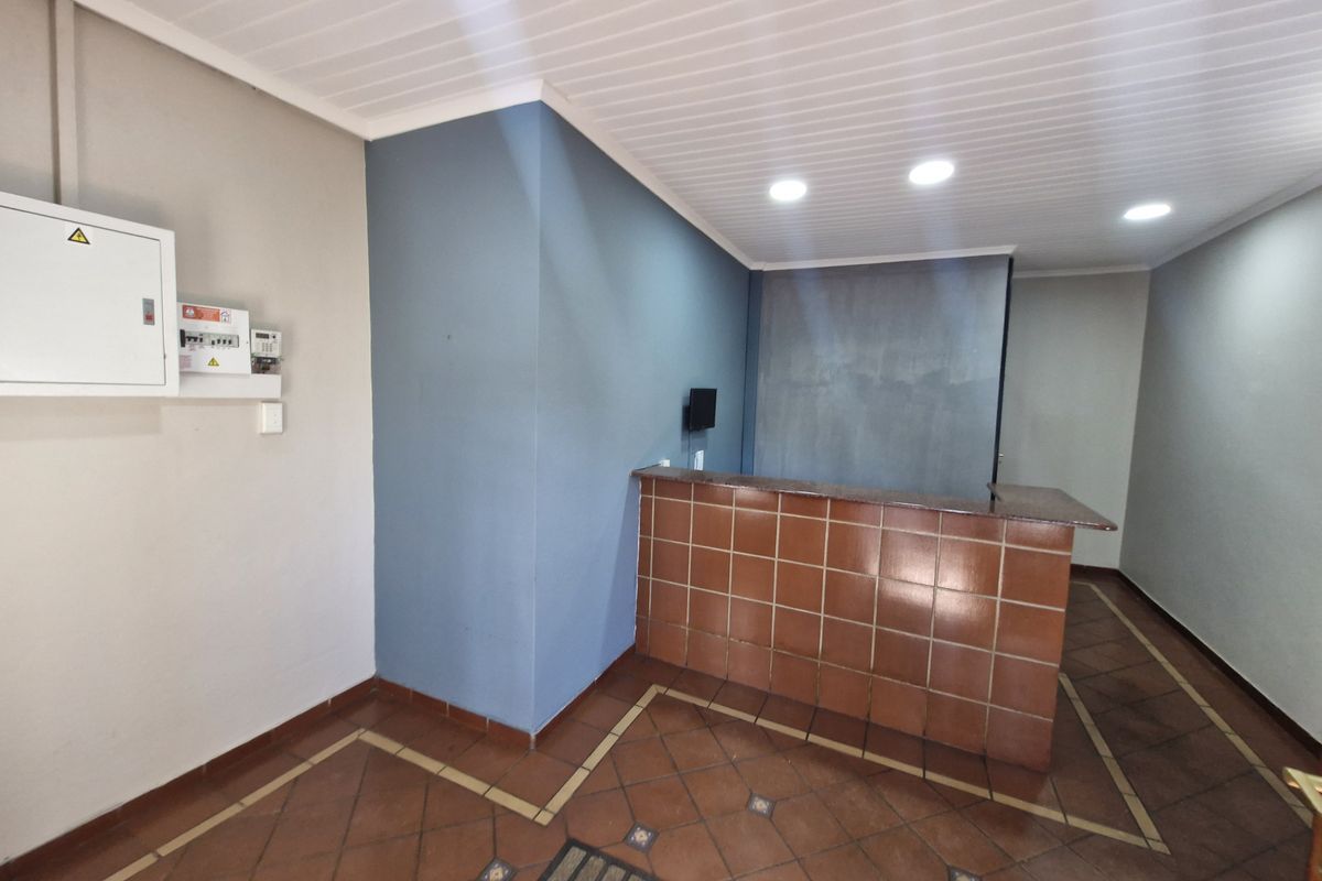 An empty office space featuring a tiled reception counter, recessed downlights, and tiled flooring with a neutral color palette.
