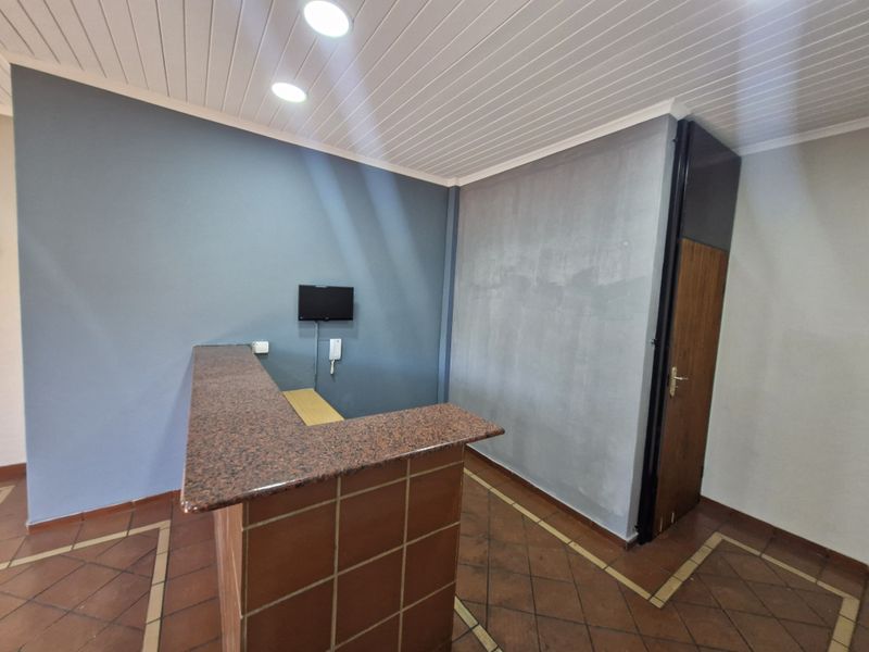 Office reception area featuring a tiled service counter with granite top, recessed lighting, and ceramic flooring.