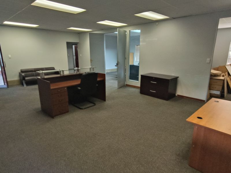 A spacious office area featuring recessed lighting, carpeted flooring, and multiple internal access points, providing a functional layout for a professional workspace.