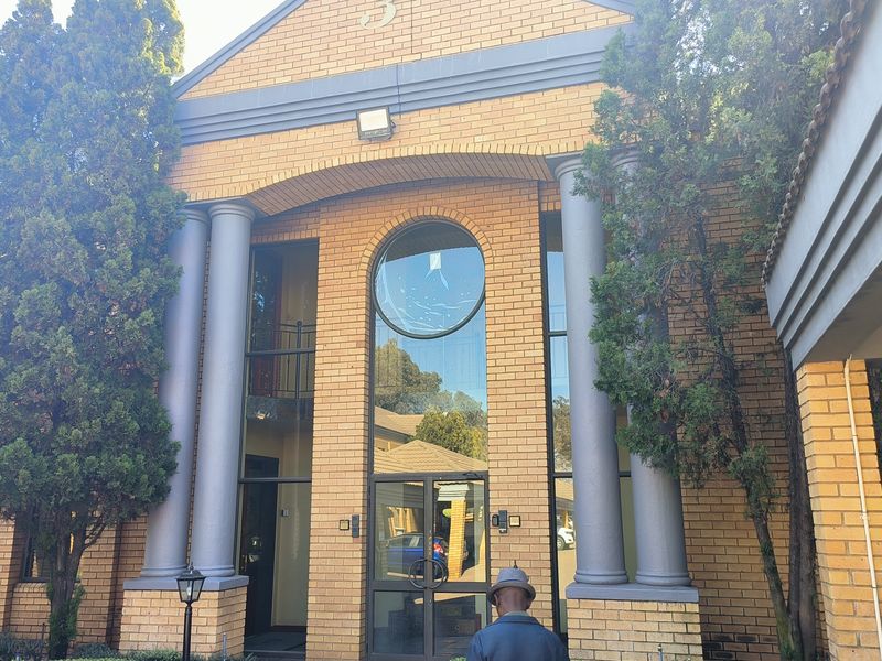 Front facade of a brick office building featuring decorative columns, a prominent circular window, and a glass-paneled entrance.