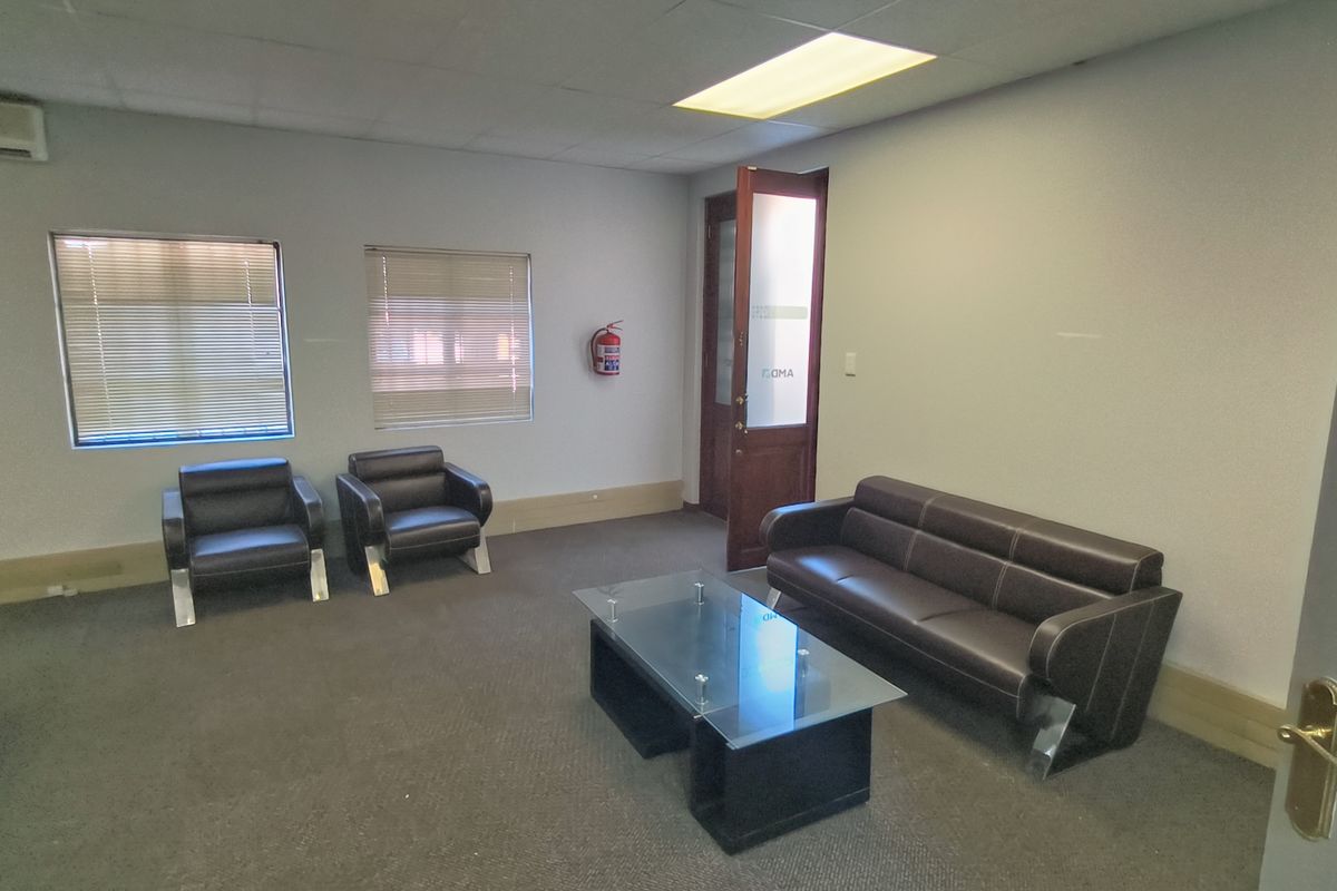 A functional office reception or waiting area featuring a drop ceiling, recessed lighting, wall-mounted air conditioning, and a fire safety unit.