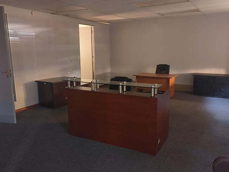 A functional office space featuring a suspended ceiling, carpeted flooring, and multiple internal access points, suitable for a professional work environment.