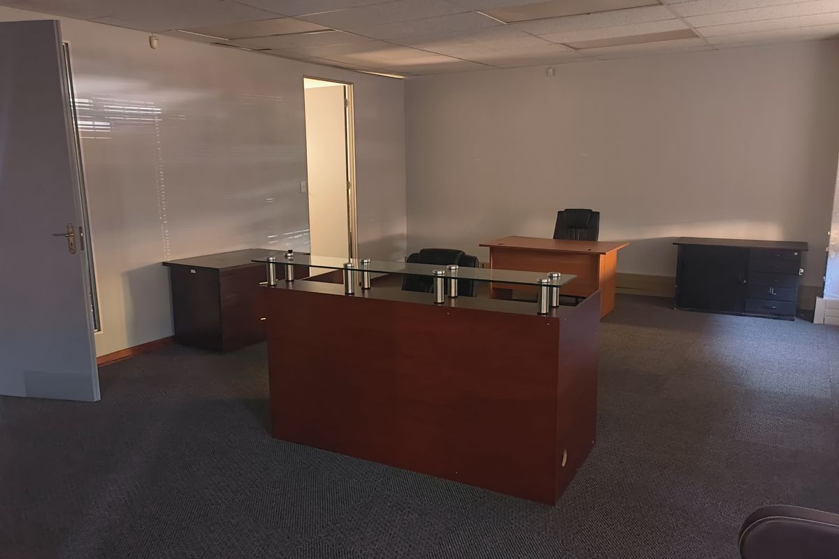 A functional office space featuring a suspended ceiling, carpeted flooring, and multiple internal access points, suitable for a professional work environment.
