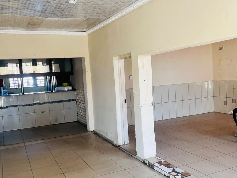 Open plan area featuring tiled flooring, a built-in serving counter, and tiled wall sections, offering a versatile space for business or commercial use.