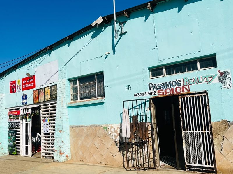 Front facade of a commercial building featuring painted brickwork, security gates, and tiled base detailing, showing signs of significant wear and maintenance requirements.