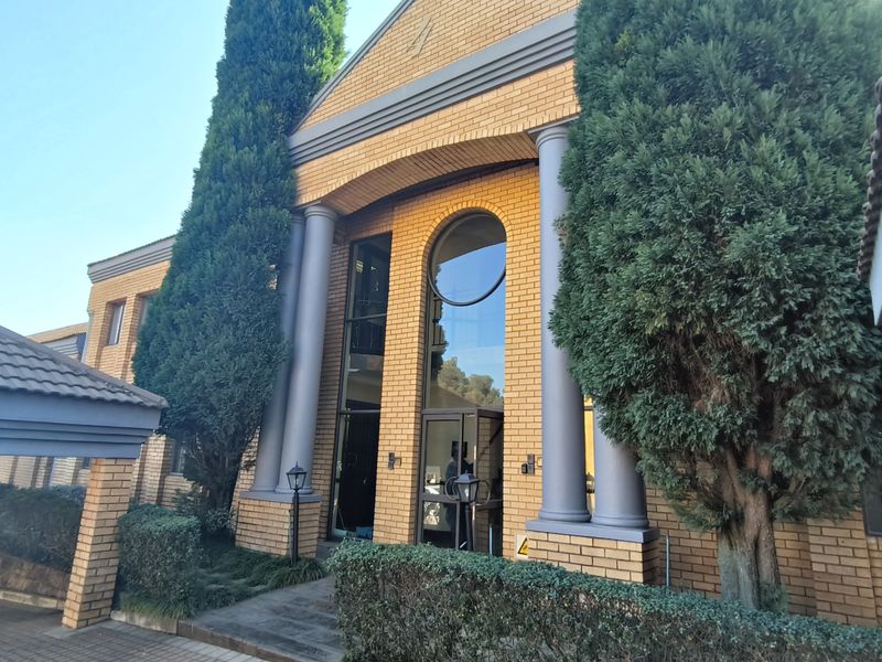 Front elevation of a professional office building featuring a prominent brick facade, classical columns, and a large arched window at the main entrance.