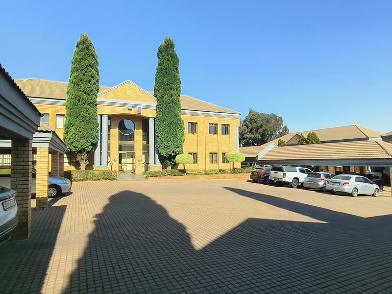 Front view of a professional office complex featuring brick architecture, covered parking bays, and well-maintained paved driveway areas.