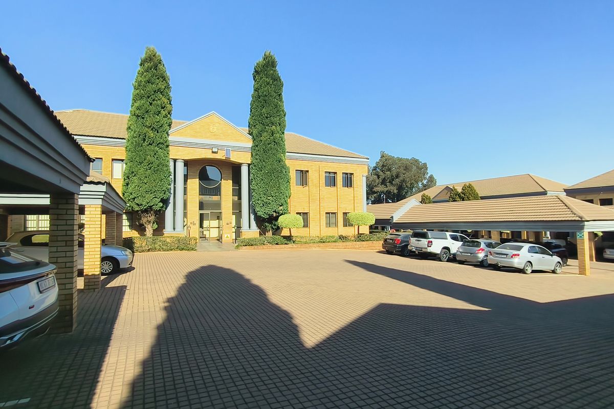 Front view of a professional office complex featuring brick architecture, covered parking bays, and well-maintained paved driveway areas.