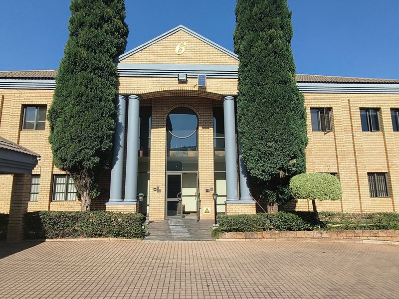 Front elevation of a professional office building featuring a brick facade, prominent columns, and a paved driveway entrance.