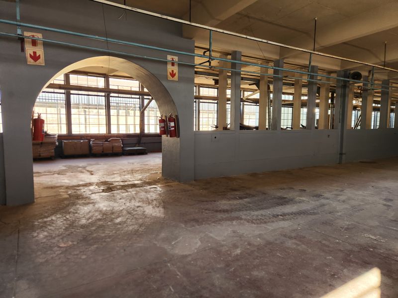 Spacious industrial utility area featuring concrete flooring, exposed ceiling infrastructure, and large steel-framed windows providing ample natural light.