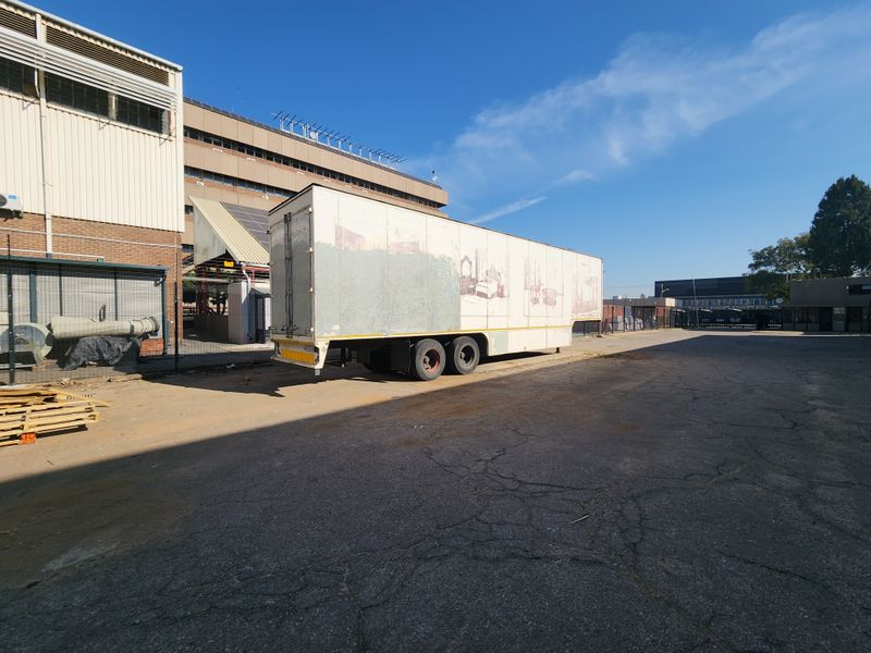 Industrial yard area featuring asphalt paving, perimeter fencing, and adjacent industrial building structure.