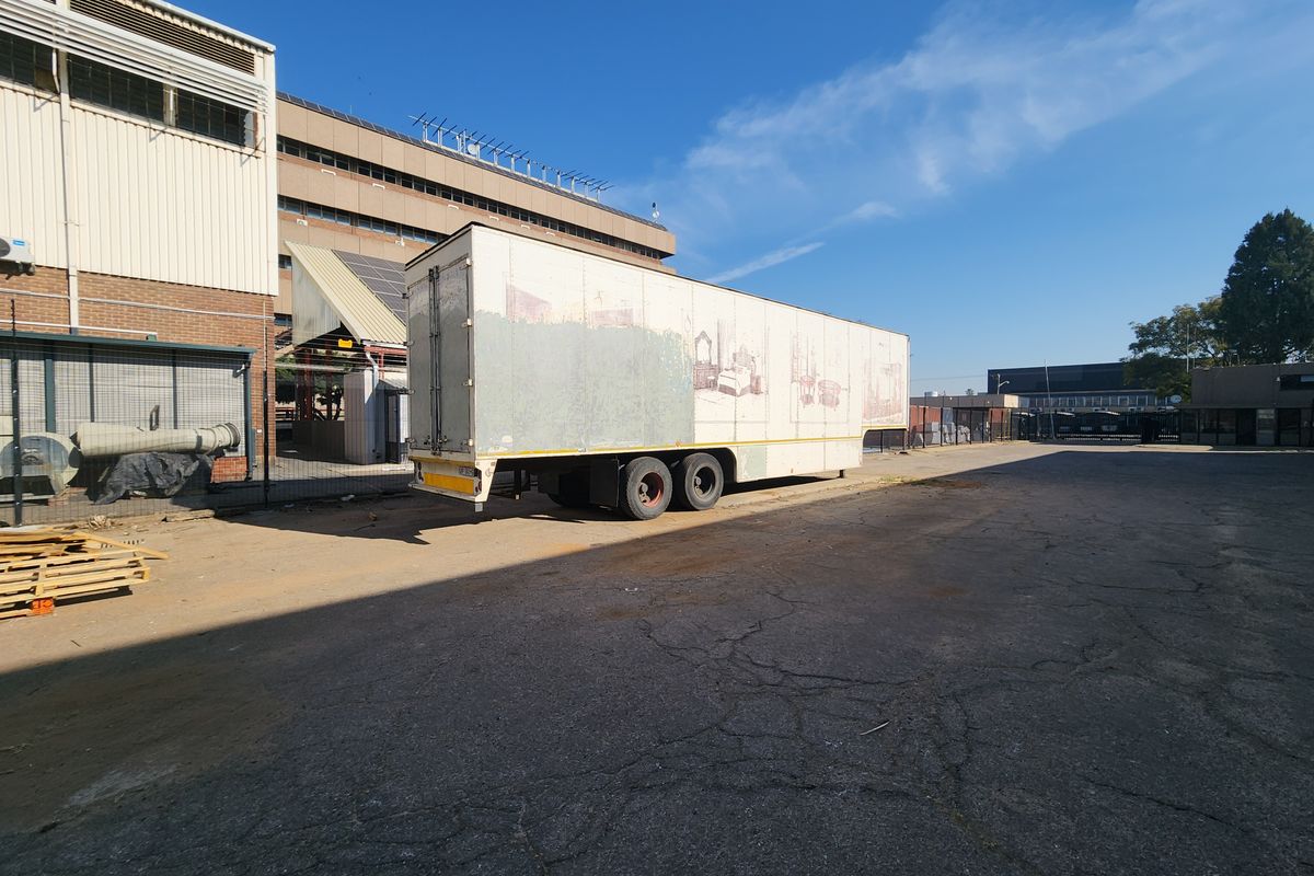 Industrial yard area featuring asphalt paving, perimeter fencing, and adjacent industrial building structure.
