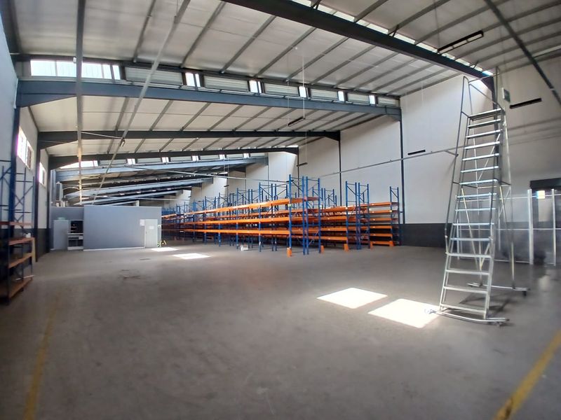 Spacious industrial warehouse featuring high ceilings, steel portal frame construction, integrated racking systems, and ample natural light through overhead skylights.