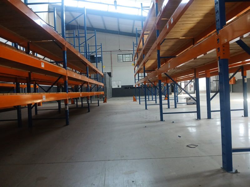 Spacious industrial warehouse unit featuring high-clearance ceilings, durable concrete flooring, and extensive built-in steel racking systems for optimal storage capacity.