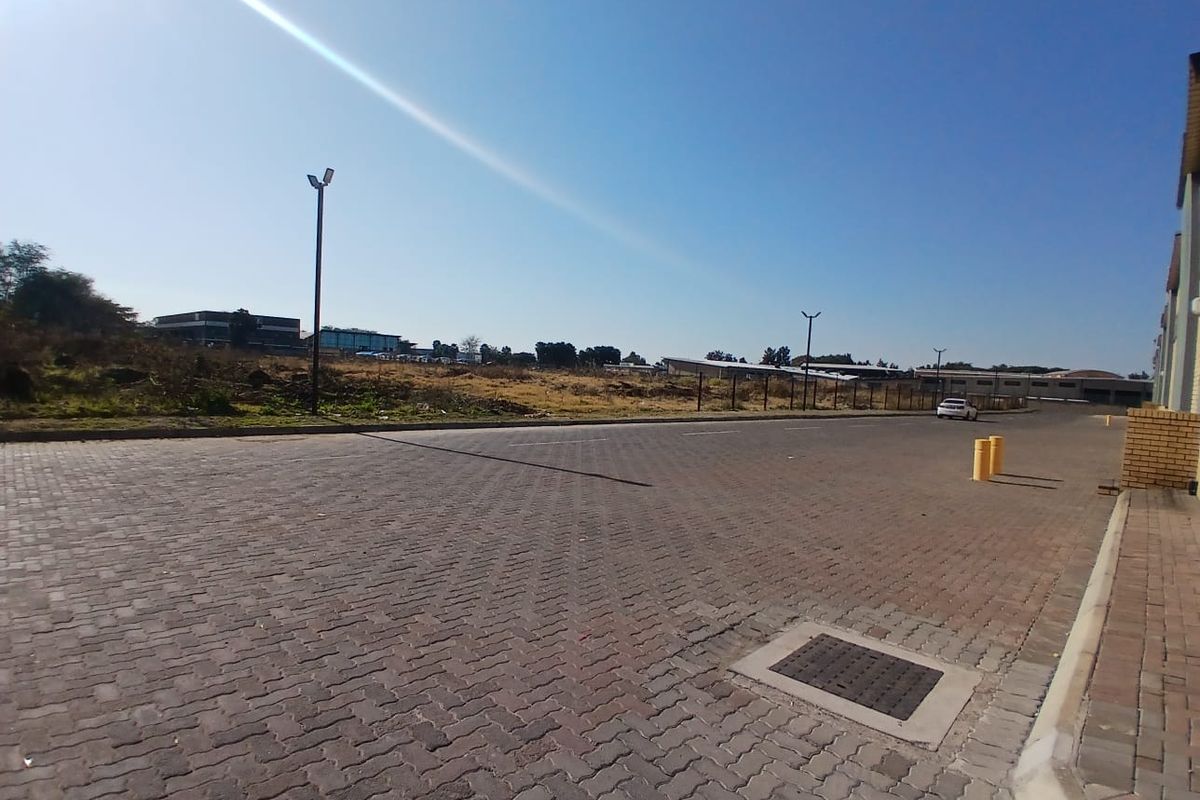 A view of the paved industrial access road and driveway, featuring street lighting, drainage infrastructure, and bollards.