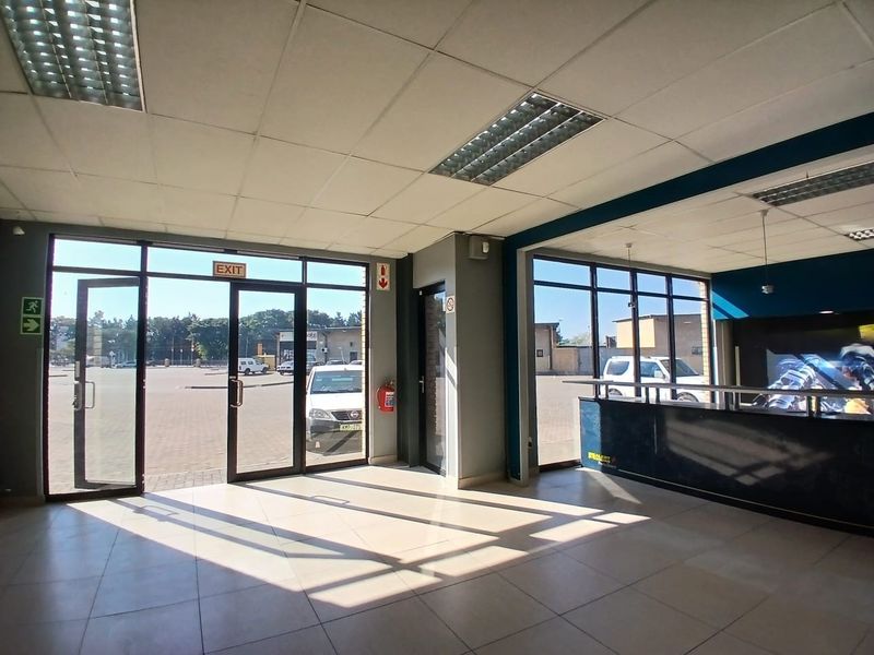 Spacious retail entrance area featuring large glass storefront windows, tiled flooring, suspended ceilings, and a built-in reception counter.