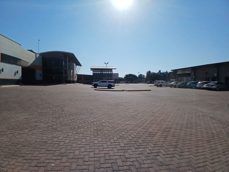 A wide-angle view of a commercial retail property featuring a large paved parking area and building facades.