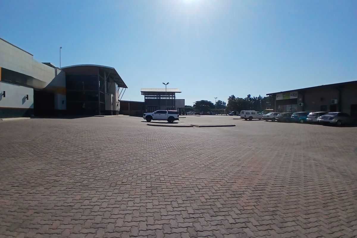 A wide-angle view of a commercial retail property featuring a large paved parking area and building facades.