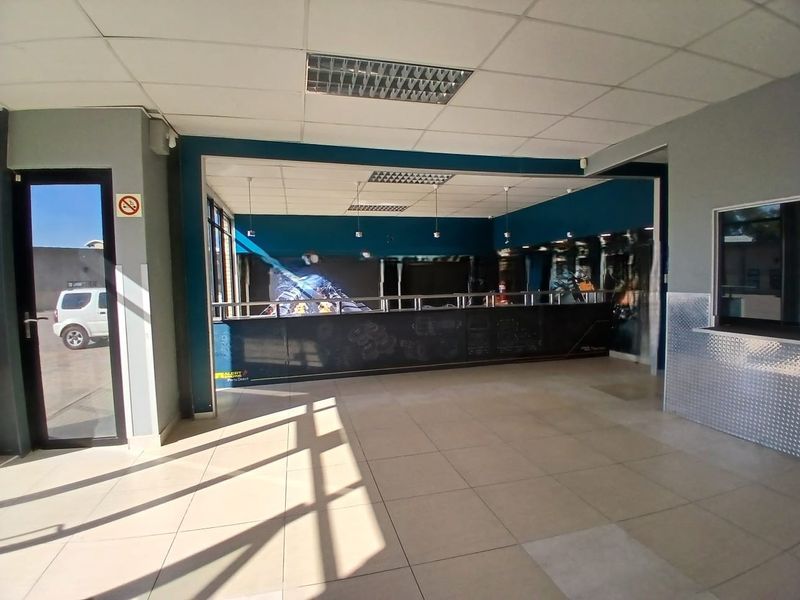Spacious retail entrance area featuring tiled flooring, a built-in service counter, and a suspended ceiling with recessed lighting.