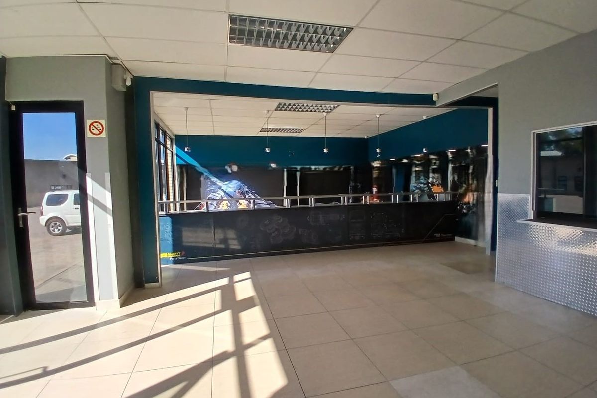 Spacious retail entrance area featuring tiled flooring, a built-in service counter, and a suspended ceiling with recessed lighting.