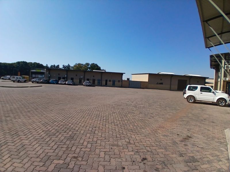 Wide-angle view of a commercial property exterior featuring a large paved parking area and multiple building units with external air conditioning installations.