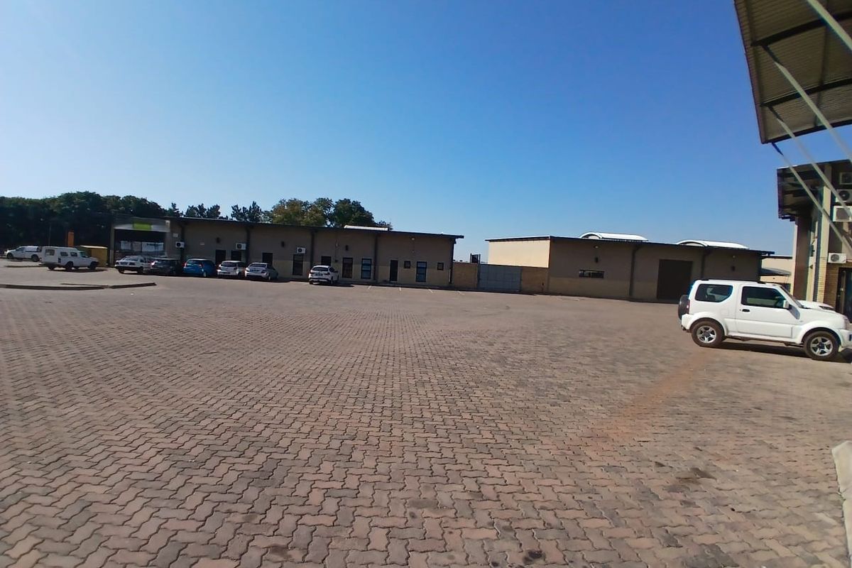 Wide-angle view of a commercial property exterior featuring a large paved parking area and multiple building units with external air conditioning installations.